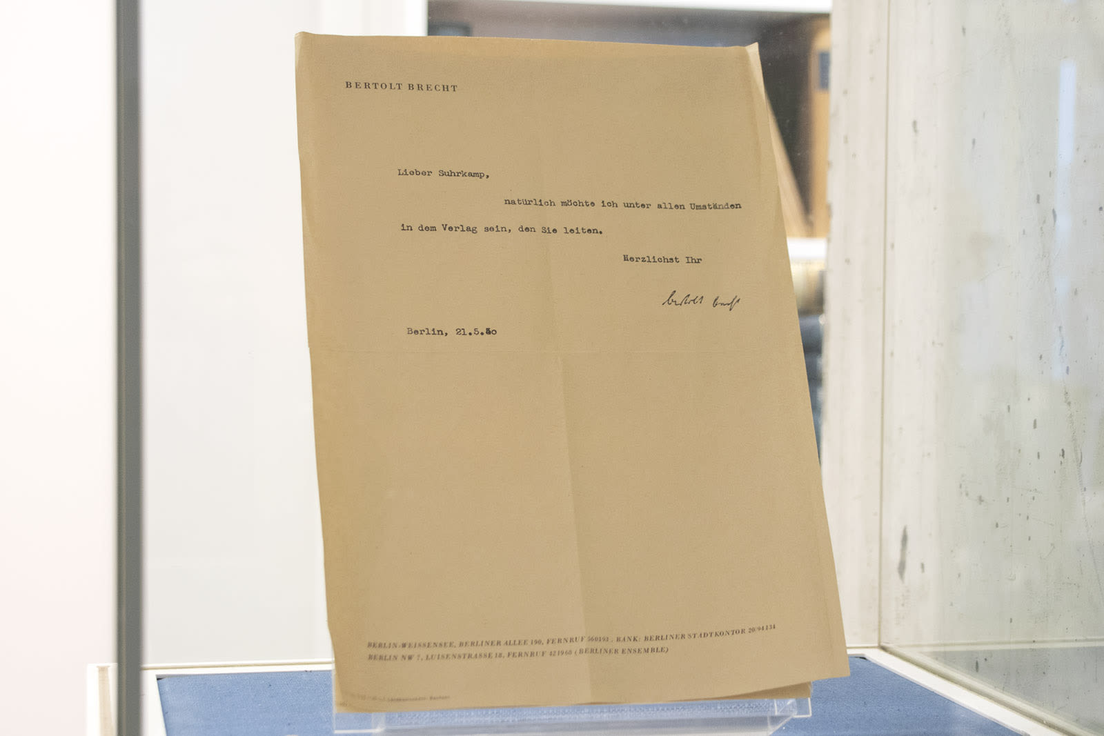 Eine Fotografie des Briefs von Bertolt Brecht an Peter Suhrkamp mit folgendem Text: »Lieber Suhrkamp, natürlich möchte ich unter allen Umständen in dem Verlag sein, den Sie leiten. Herzlichst Ihr Bertolt Brecht.«
