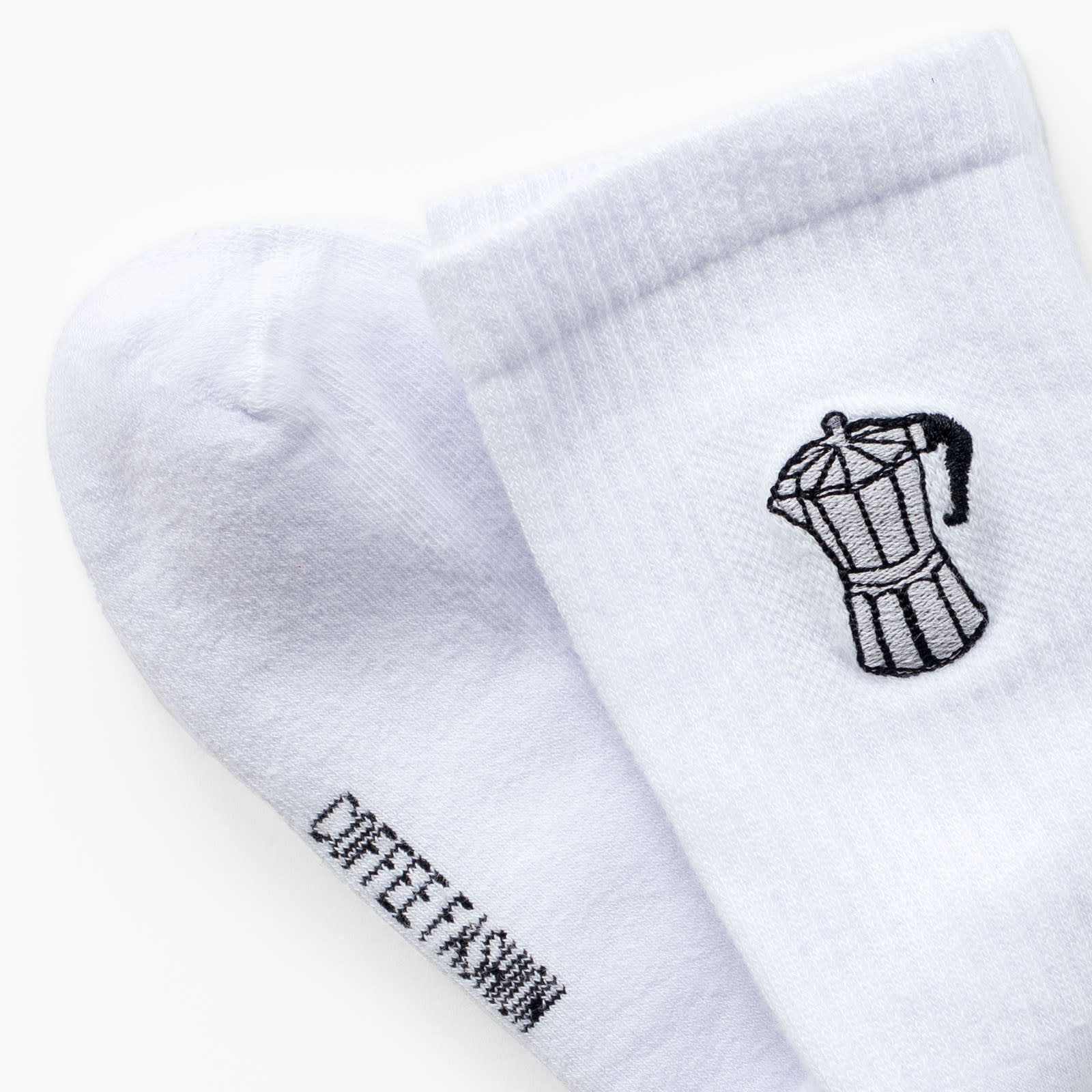 Ein Paar Socken, auf die eine Bialetti-Kanne gestickt ist. 