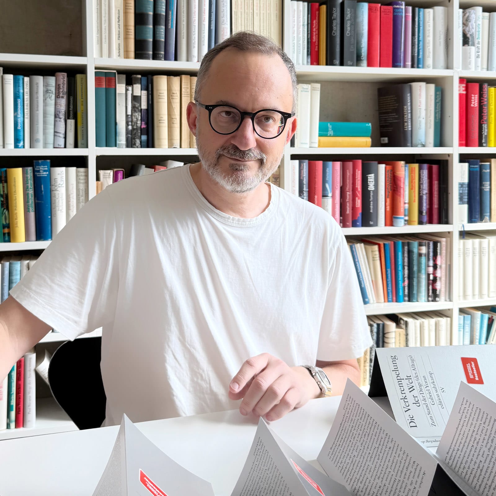 Gabriel Yoran guckt in die Kamera und signiert eines seiner Bücher.