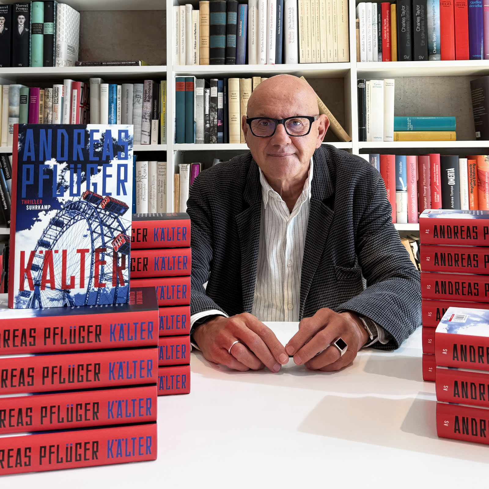 Ein Foto von Andreas Pflüger, neben ihm befindet sich ein Stapel seiner Bücher.