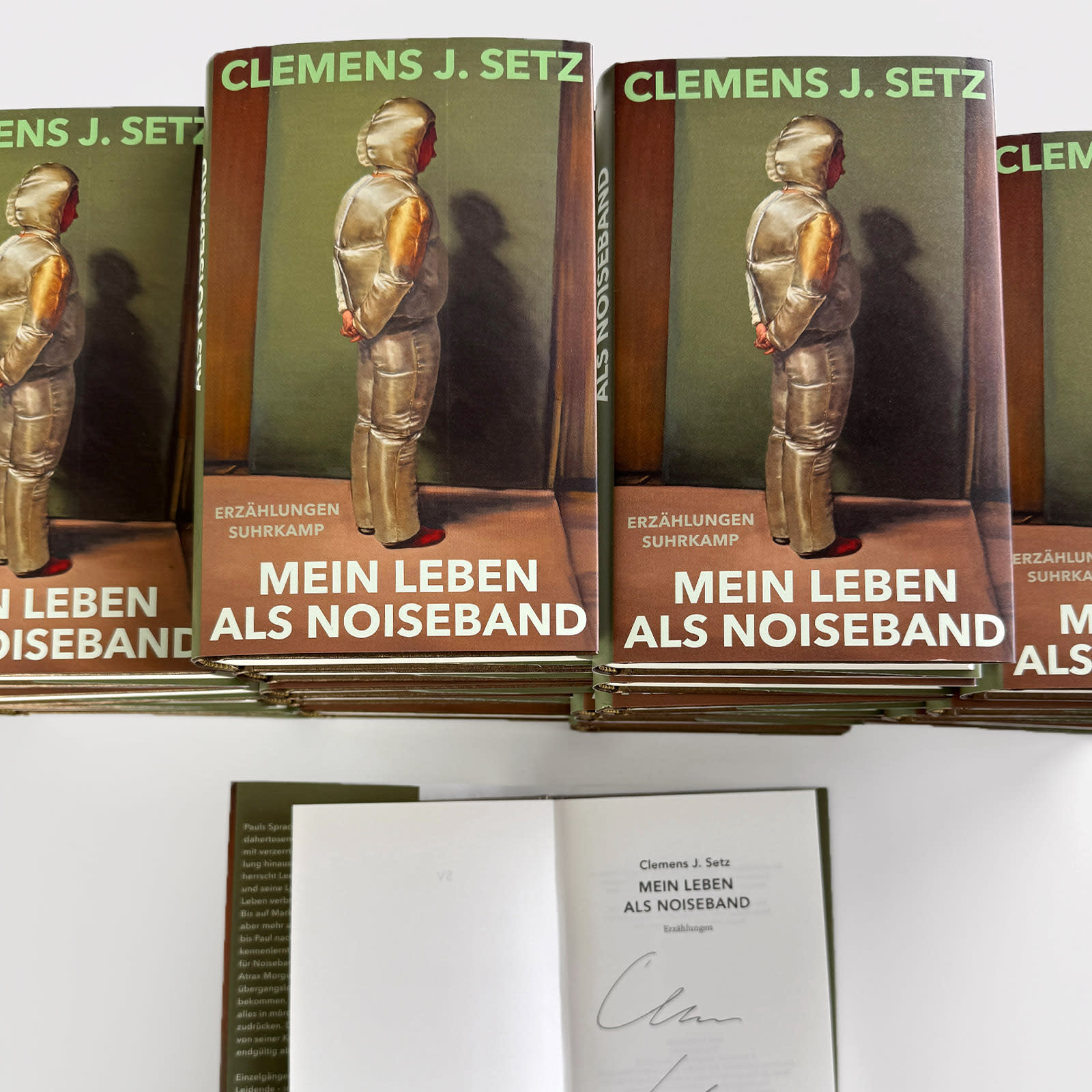 Mehrere Bücherstapel und ein signiertes Exemplar des Buchs "Mein Leben als Noiseband"