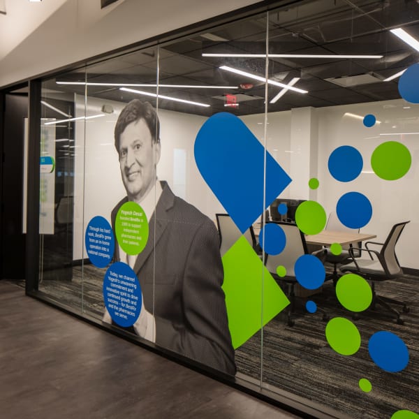 Window graphics show large-scale portrait with blue and green geometric elements on glass partition.