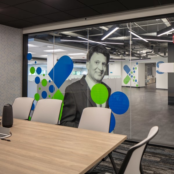 Environmental branding combines photo portrait and colorful circles on frosted glass viewed from conference room.