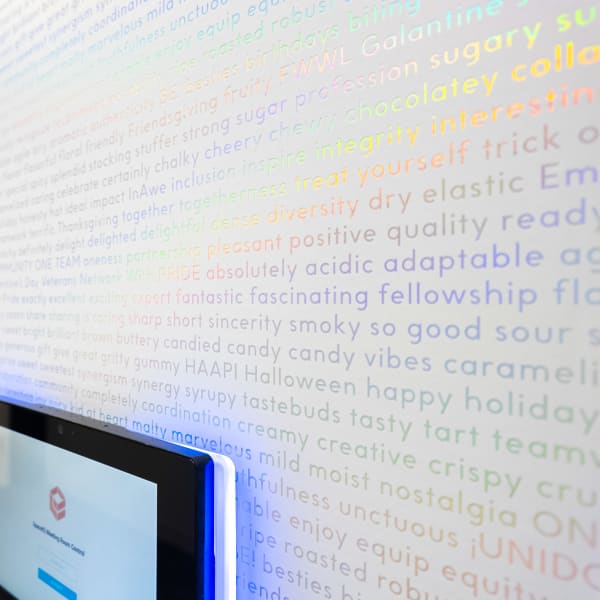 Custom holographic wallpaper with rainbow iridescent text installed beside doorway with digital screen mount.