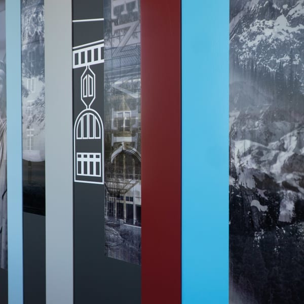 Sectioned custom wallpaper panels on office wall graphics featuring white line-art building icons over colorful vertical stripes and photography.