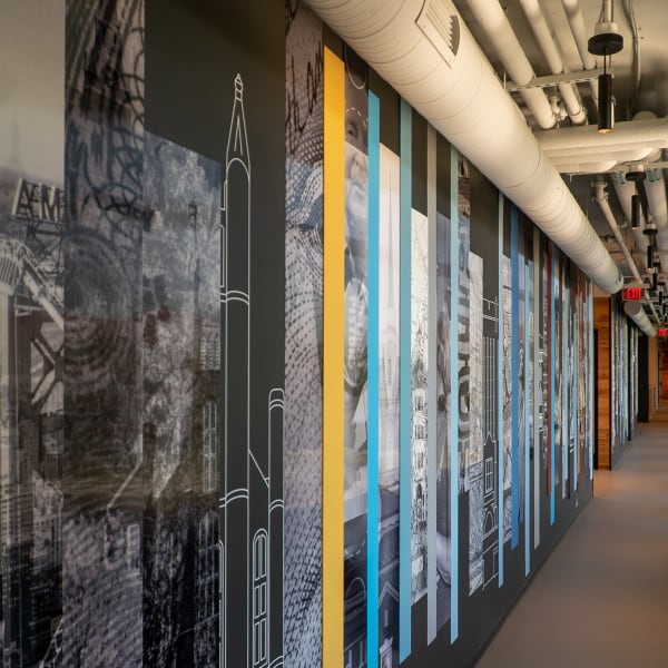 Long office hallway showcasing lenticular graphics murals with layered historic images and geometric overlays on both walls.
