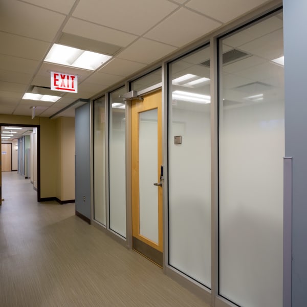 Office glass frosting provides privacy for medical exam rooms along a hallway, with clear transoms above.