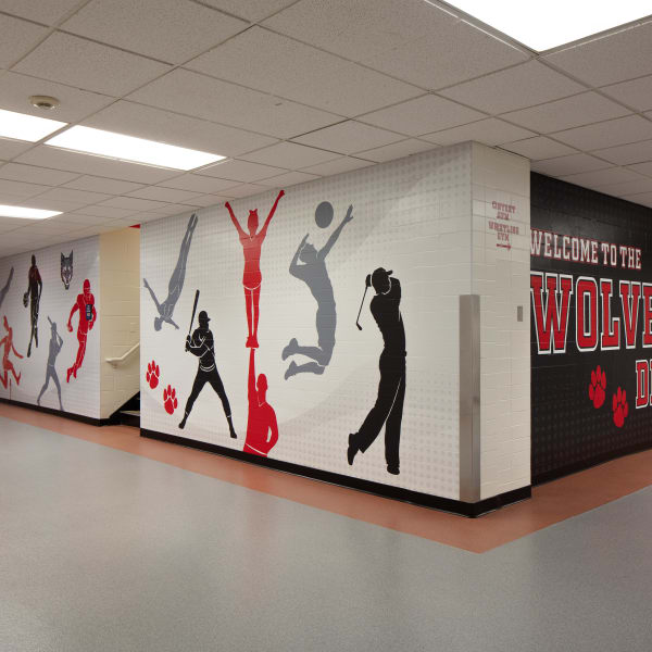 Environmental branding on hallway corner features athletic silhouettes and Welcome to the Wolves Den message.