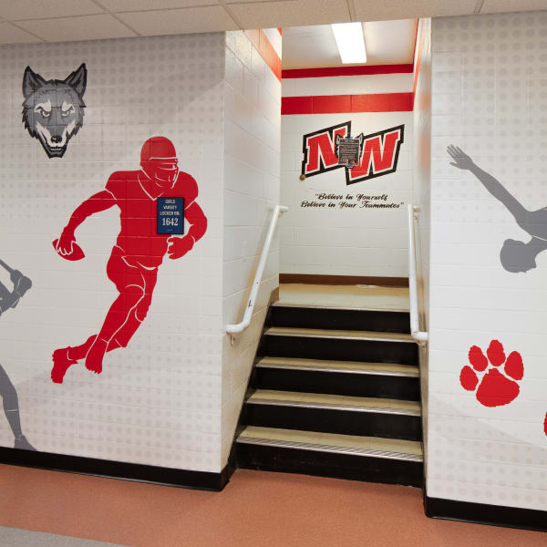 Environmental branding surrounds stairwell entrance with football player, wolf head, NW logo, and paw graphics.