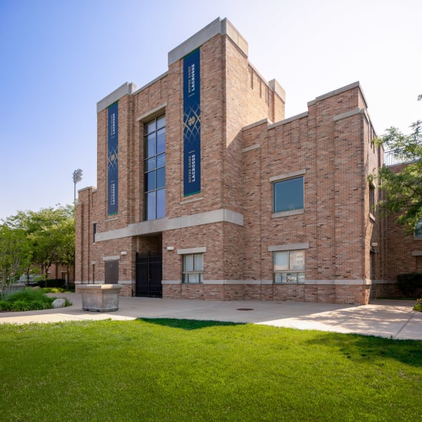 Notre Dame Lacrosse Stadium exterior with blue vertical banners flanking tall glass entrance on brick building.