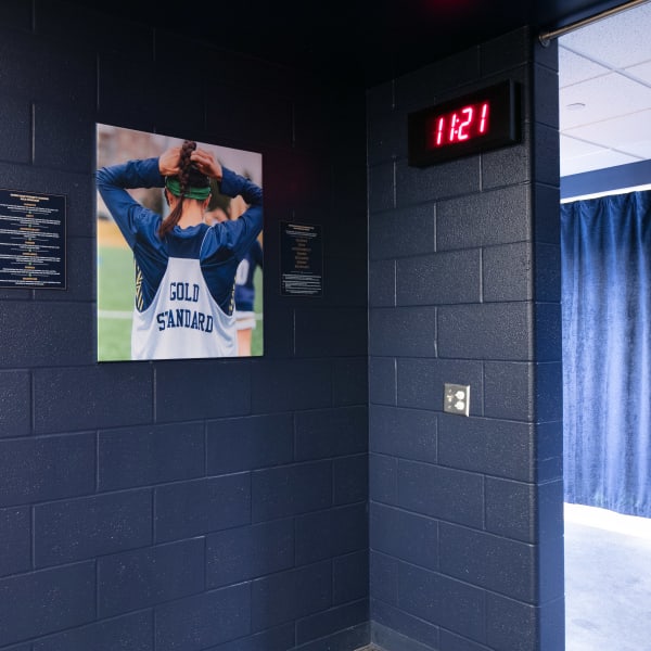 Photo in school locker room showing player adjusting headband, mounted on navy painted cinder block wall.