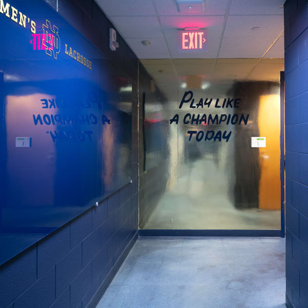 Inspiring graphics in locker room hallway with frosted glass reading 'Play like a champion today' leading to exit.