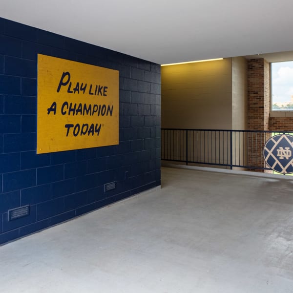 Team saying mounted on stadium concourse wall reading 'Play like a champion today' in gold on blue.