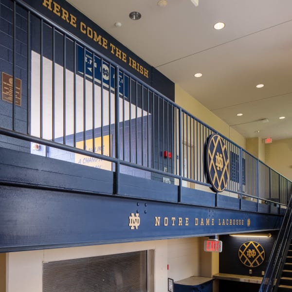 School dimensional logo sign visible on upper level railing with 'Here Come the Irish' text above stairs.