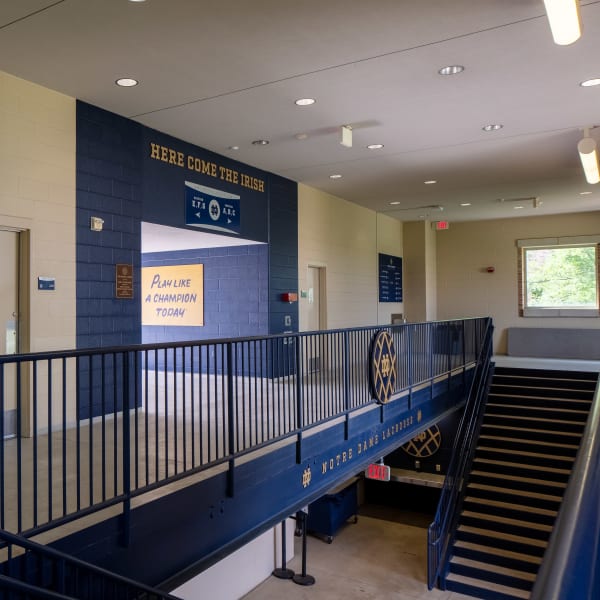 School stadium signage reading 'Here Come the Irish' mounted on navy wall above balcony with motivational yellow panel.