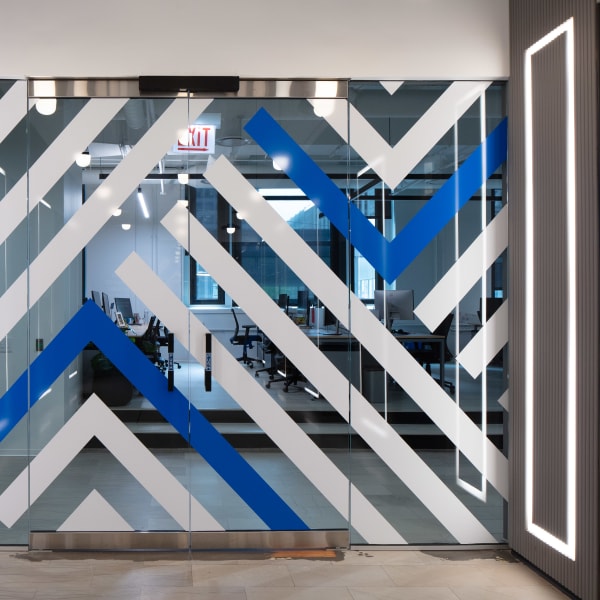 Geometric diagonal stripe pattern in blue, gray, and white vinyl film applied to glass office doors.