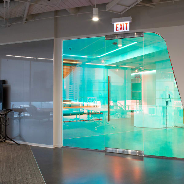 Office window frosting in solid turquoise film on large angled glass conference room wall.