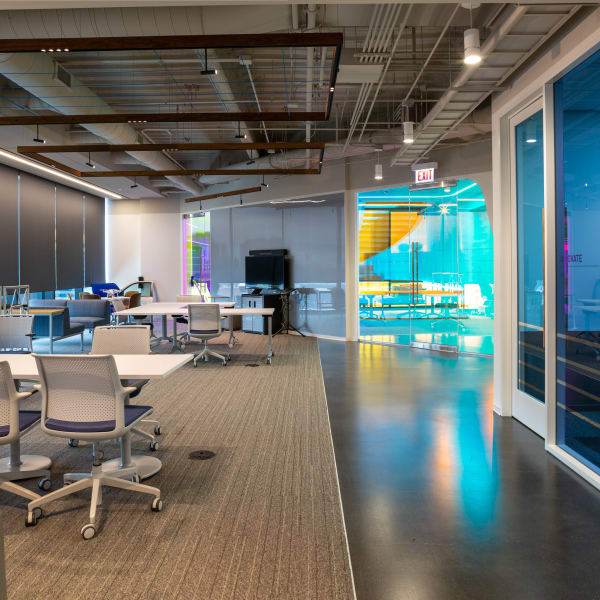 Office wall graphics and window graphics in turquoise, yellow, and gray tones across open workspace.