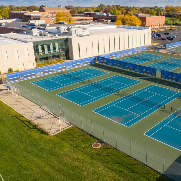 Aerial view of outdoor mesh banners installed around multiple tennis courts at Highland Park High School.