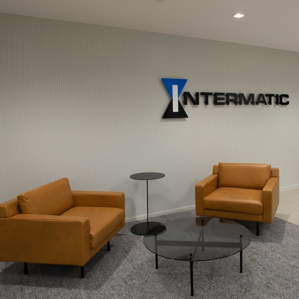 Office wall graphics featuring dimensional lettering displayed above a reception area with modern furniture and desk.