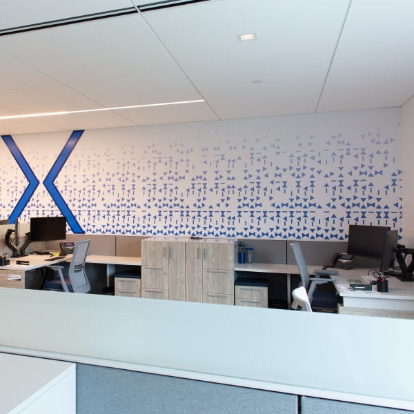 Environmental branding featuring large office wall graphics with blue geometric shapes spanning workspace wall.