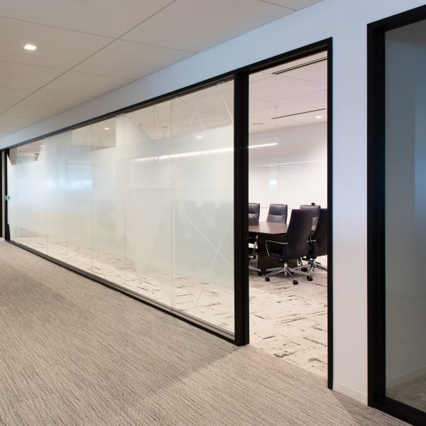 Office window frosting featuring subtle geometric etched pattern on glass conference room walls along hallway.