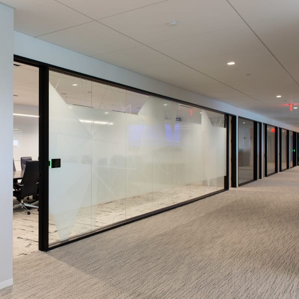 Frosted glass panels with geometric patterns along hallway adjacent to conference room entrance.