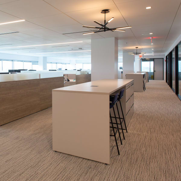 Wide view of open office floor with cubicle workstations and ceiling-mounted lighting fixtures.
