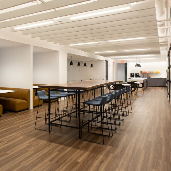 Office breakroom featuring lounge seating booths and central high-top tables with bar seating.