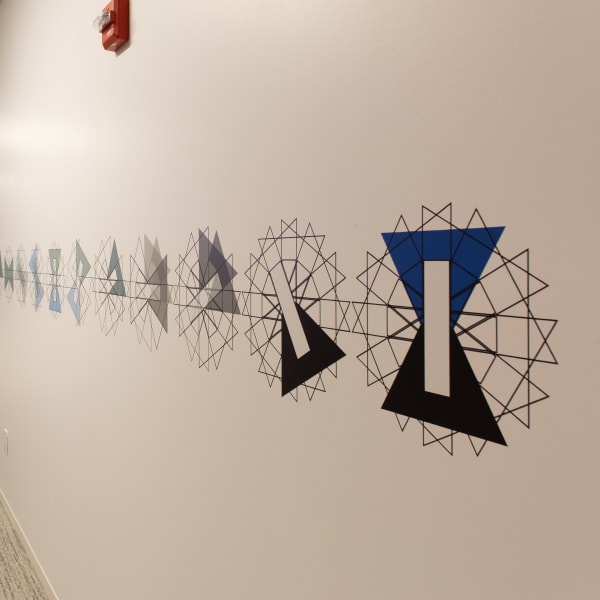 Environmental branding showcasing full-length geometric wall graphics along office corridor with repeating pattern.