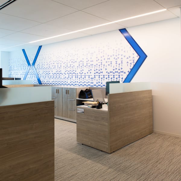 Environmental graphics featuring large geometric pattern and logo near reception desk in open area.