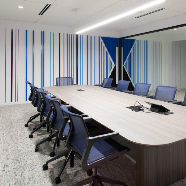 Environmental branding showing vertical blue striped graphics with large central logo on conference room wall.