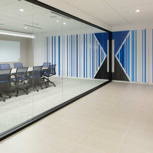 Environmental graphics on exterior conference room wall featuring vertical stripes and logo viewed from hallway.