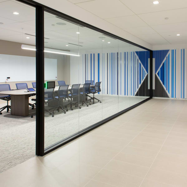 Environmental graphics showing striped wall design with central logo on conference room behind frosted glass.