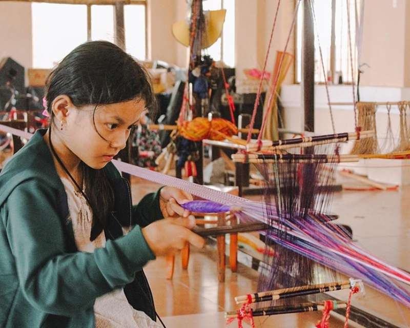 Cô gái trẻ trải nghiệm dệt vải thổ cẩm tại làng dệt Mỹ Nghiệp