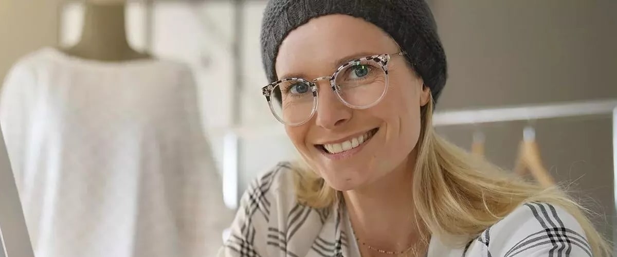 Junge Frau sitzt lächelnd an einem Schreibtisch.