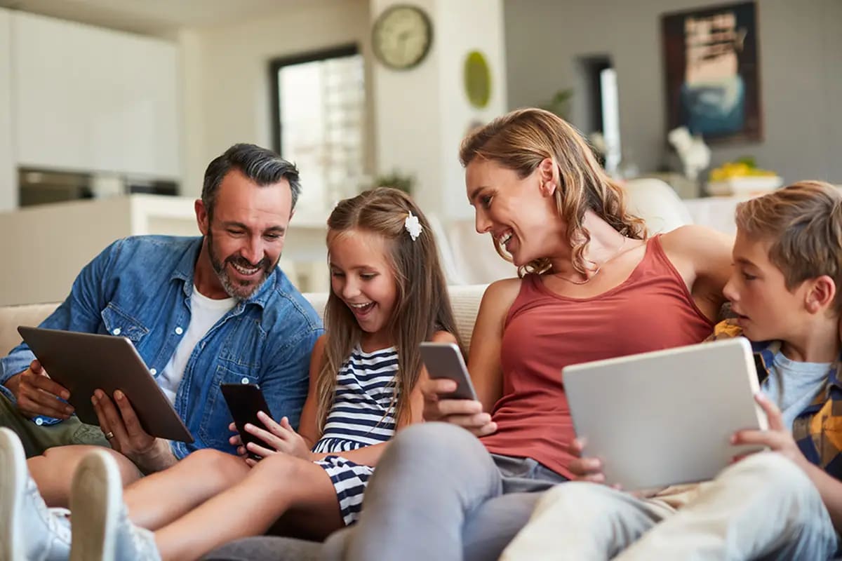 Familie mit Handys und Tablets auf dem Sofa