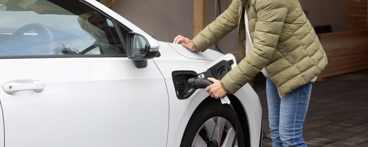 Person schließt ein Elektroauto an ein Ladekabel an.