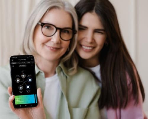 Zwei Frauen halten ein Handy in die Kamera.