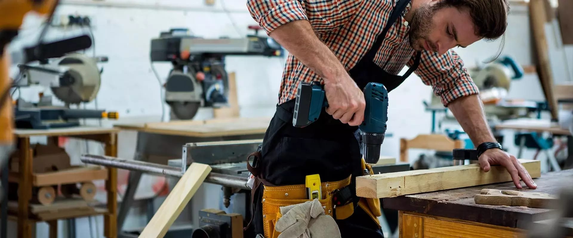 Tischler in der Werkstatt mit einem Bohrer in der Hand.