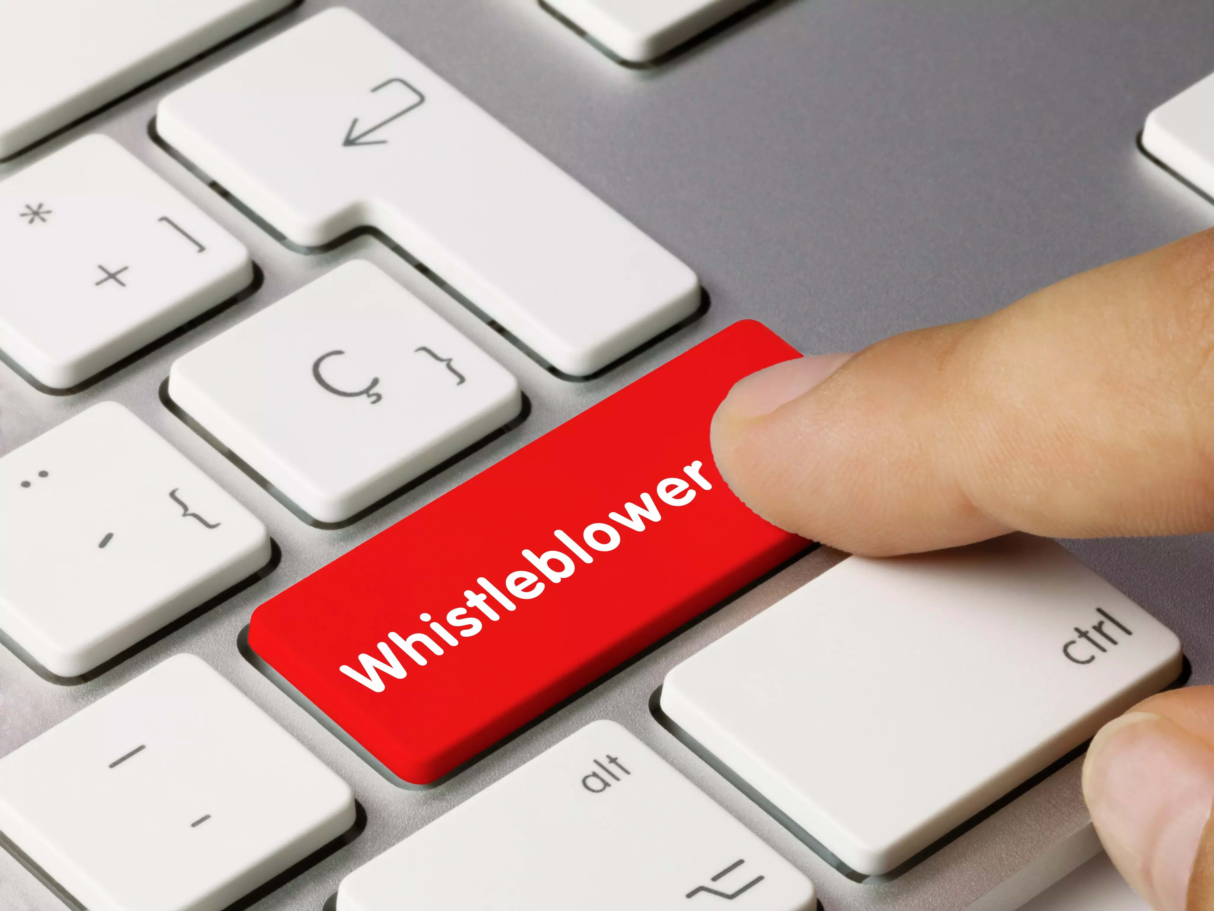 Finger drückt rote Taste mit der Aufschrift „Whistleblower“ auf Computertastatur.