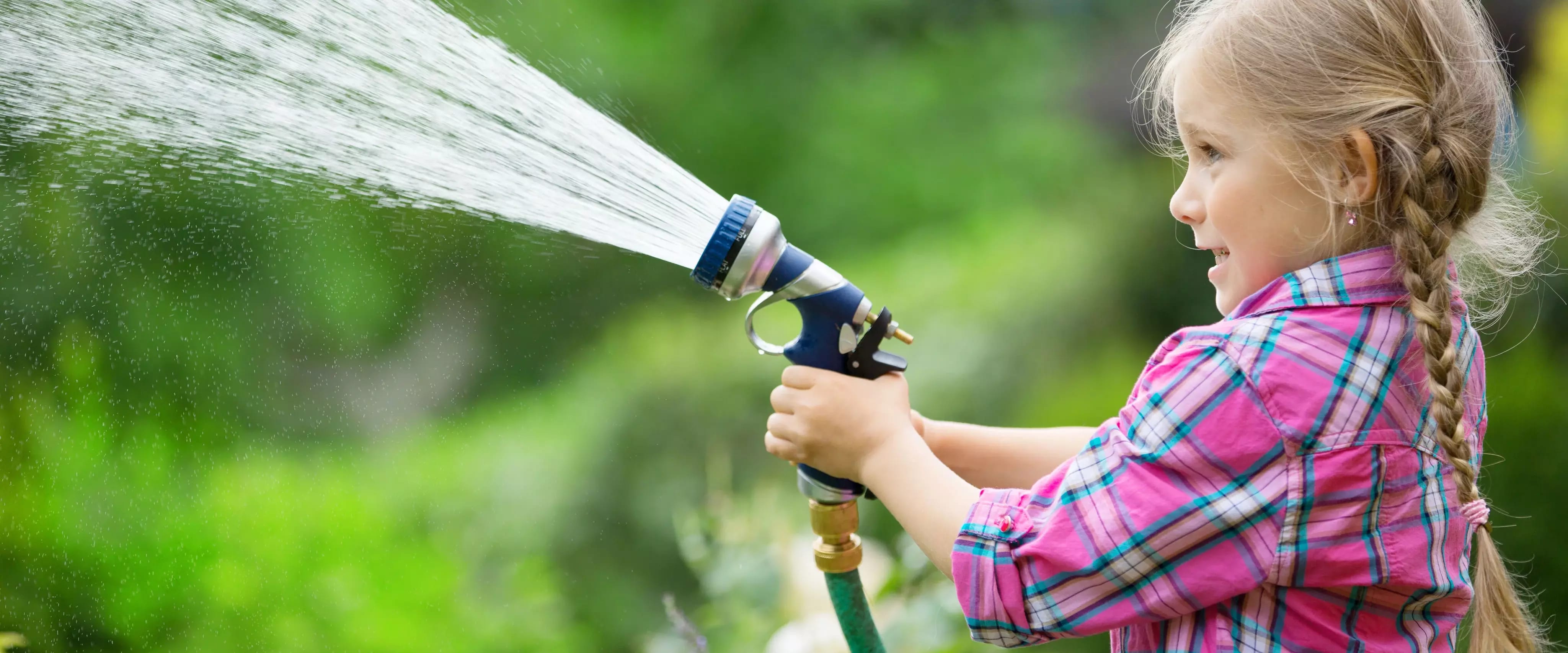 Kind mit Gartenschlauch