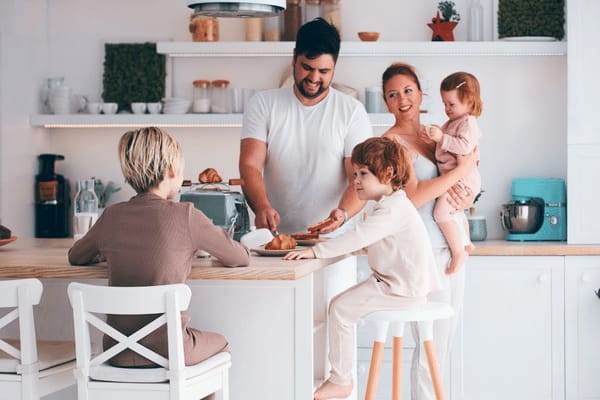 Junge Familie mit drei Kindern frühstückt in der Küche.