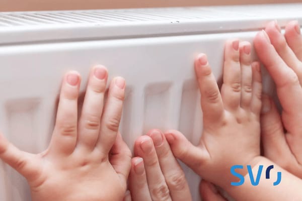 Kleine und große Hände wärmen sich am Heizkörper.