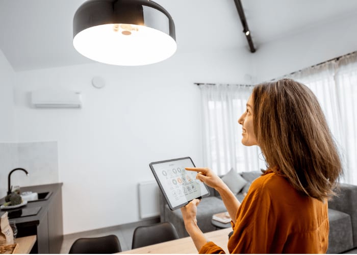 Frau steuert ihre Lampe mit einem Tablet.