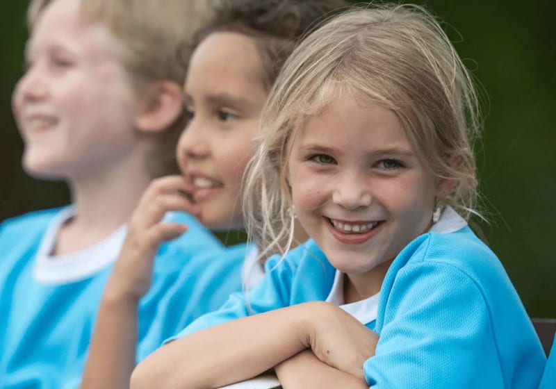 Eine Gruppe von lächelnden Kindern in blauen Trikots.