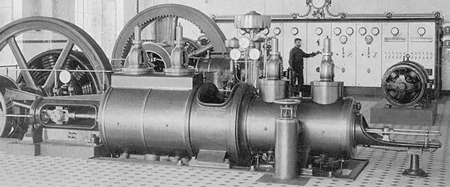 Historische Dampfmaschine in einer alten Maschinenhalle mit Bedienelementen und Kontrollinstrumenten.