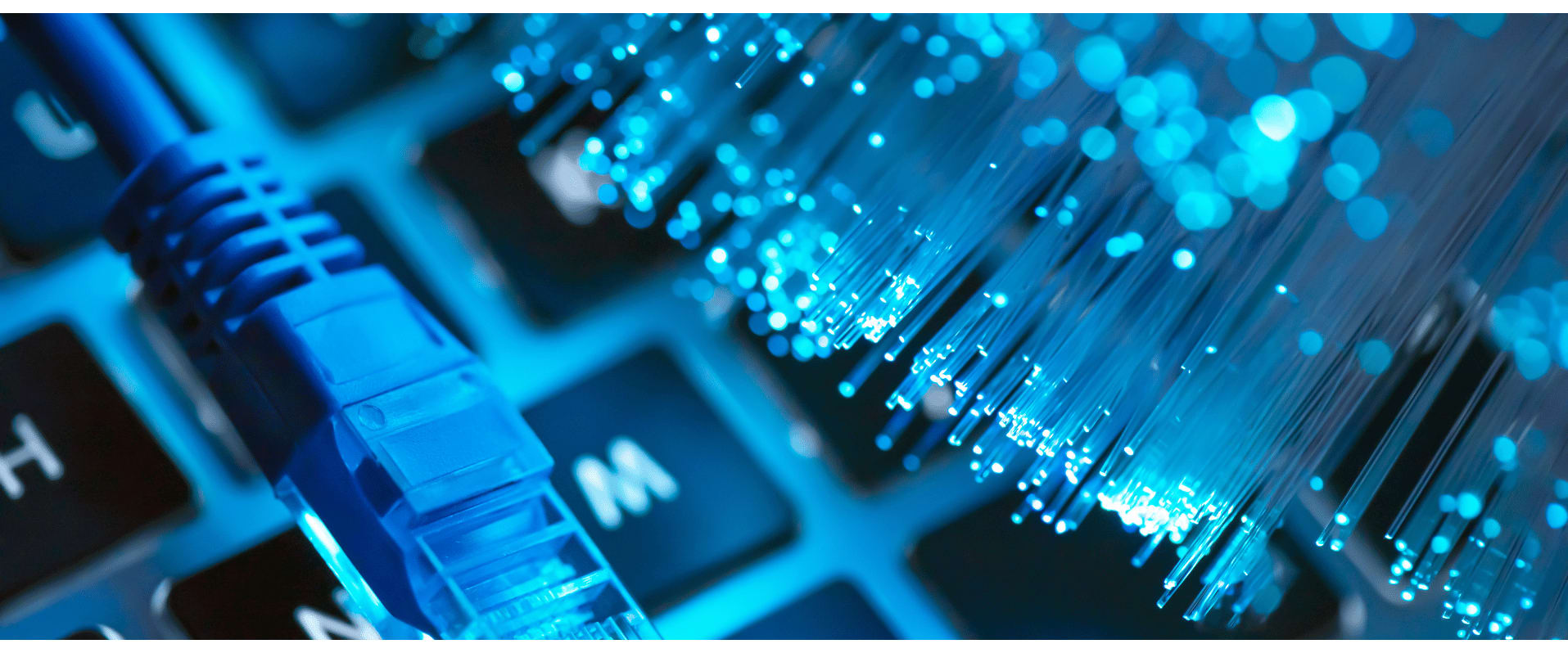 Nahaufnahme eines Netzwerkkabels neben leuchtenden Glasfaserkabeln auf einer Tastatur – symbolisch für digitale Infrastruktur und Highspeed-Internet.