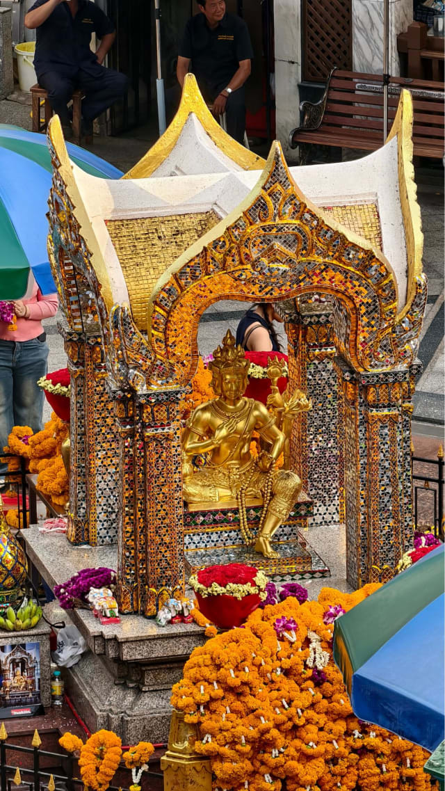 The gold Four-Faced Brahma image inside its shrine pavilion, decorated with marigold garlands