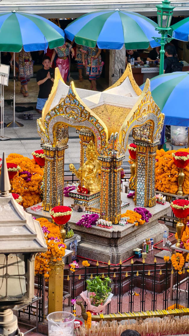 Elevated view of the shrine pavilion with traditional dancers performing an offering and devotees paying respects